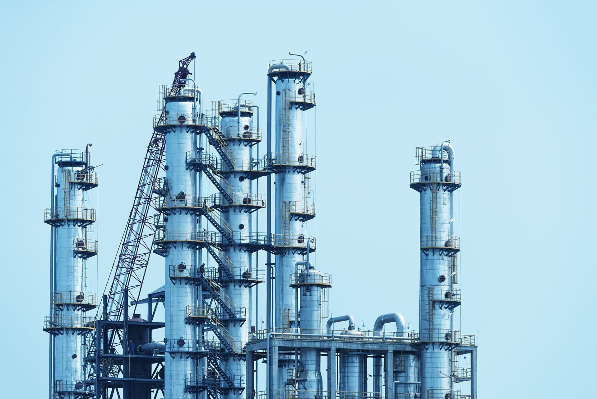 Industrial distillation towers against a clear blue sky.