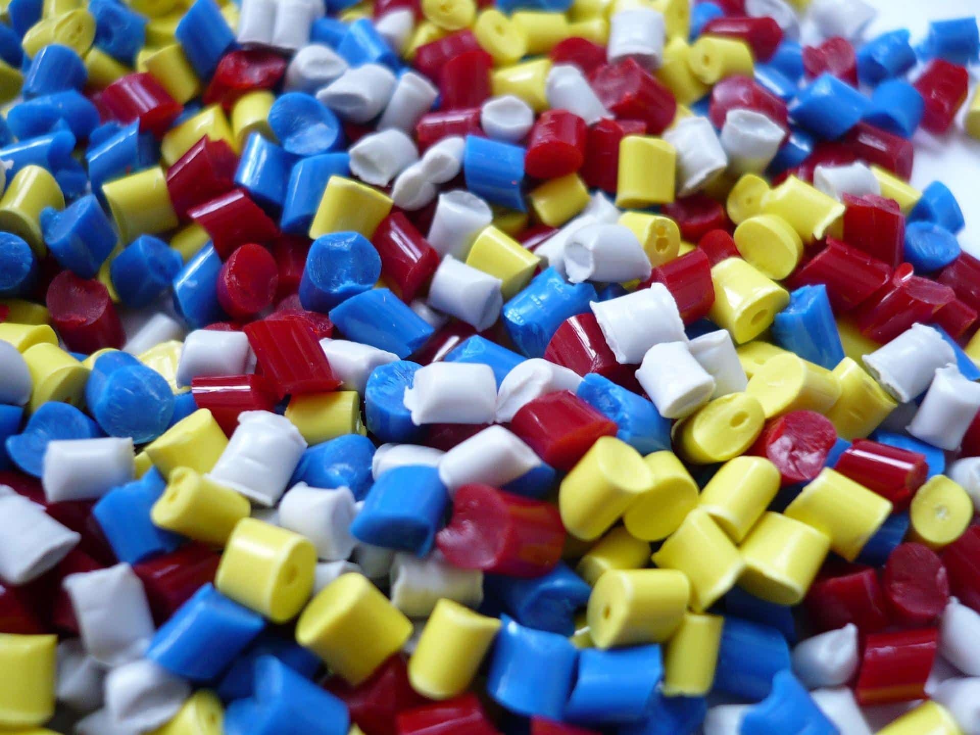 Close-up of a colorful pile of plastic pellets in red, blue, yellow, and white.