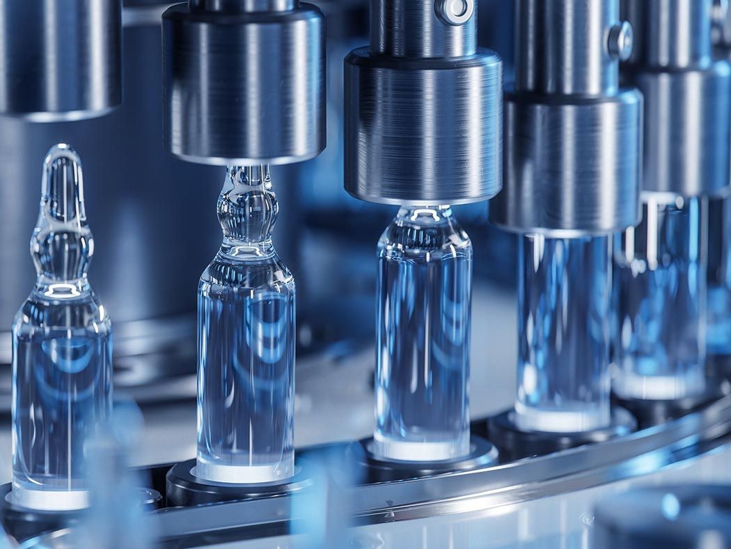 Close-up of a pharmaceutical production line with glass vials being filled by machinery.